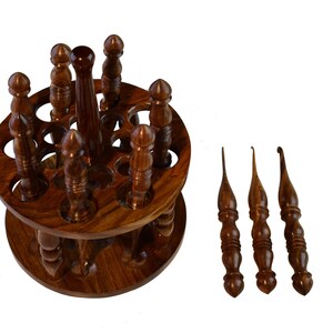 May include: A wooden spinning stand with 12 slots for holding crochet hooks. The stand is made of dark brown wood and has a smooth finish. Three additional crochet hooks are shown separately.