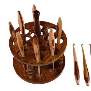 May include: A wooden crochet hook holder with 18 holes and a rotating base. The holder is filled with a variety of wooden crochet hooks. There are also three additional crochet hooks lying on a white surface.