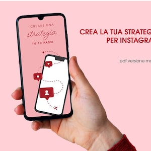 Può includere: Uno smartphone mostra uno schermo rosa con il testo "CREARE UNA strategia IN 10 PASSI" e "CREA LA TUA STRATEGIA PER INSTAGRAM". Lo schermo del telefono mostra icone di social media e una linea tratteggiata. Lo sfondo è rosa.