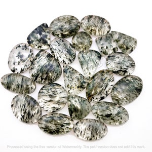 Puede incluir: Una colección de 18 cabujones ovalados de piedra preciosa translúcida verde y negra. Las piedras tienen un aspecto nublado y veteado con inclusiones negras y verdes.