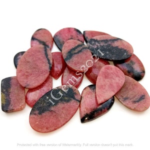 May include: A collection of pink and black gemstone cabochons in various pear and oval shapes. The stones have a striated pattern and are arranged in a pile.