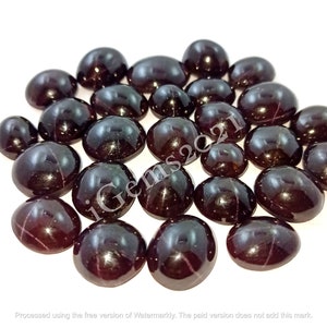 May include: A collection of 20 dark red gemstone cabochons with a star-like pattern. The cabochons are oval shaped and have a smooth, polished surface.