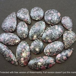 Peut inclure: Une collection de 16 cabochons de pierres précieuses noires et roses avec un motif moucheté. Les cabochons sont de formes et de tailles variées, notamment ovales, en forme de larme et ronds.