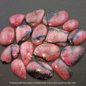 May include: A collection of 15 pink and black gemstone cabochons. The cabochons are various shapes and sizes, including oval, pear, and rectangular. The stones have a smooth, polished finish.
