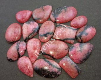 Puede incluir: Una colección de 15 cabujones de piedras preciosas rosas y negras. Los cabujones son de varias formas y tamaños, incluyendo ovalados, en forma de pera y rectangulares. Las piedras tienen un acabado liso y pulido.