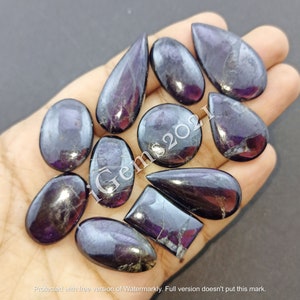 Puede incluir: Una colecci&oacute;n de 12 cabujones de piedras preciosas de color p&uacute;rpura y negro en varias formas, incluyendo ovalada, de l&aacute;grima y rectangular. Las piedras preciosas tienen un acabado brillante e iridiscente.