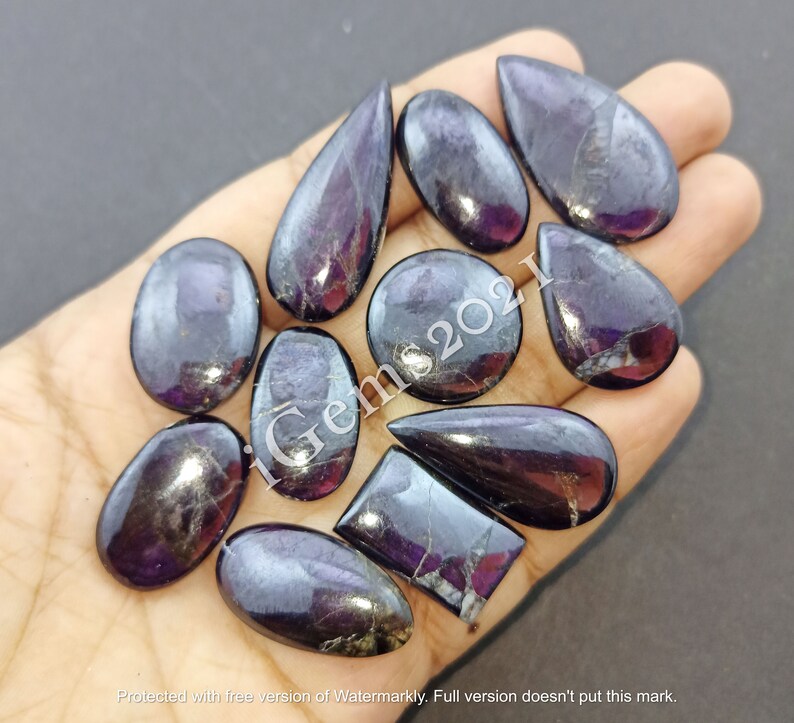 Puede incluir: Una colecci&oacute;n de 12 cabujones de piedras preciosas de color p&uacute;rpura y negro en varias formas, incluyendo ovalada, de l&aacute;grima y rectangular. Las piedras preciosas tienen un acabado brillante e iridiscente.