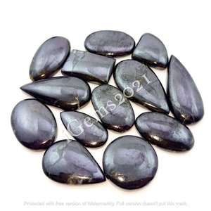 Puede incluir: Una colecci&oacute;n de 12 cabujones de piedras preciosas negras iridiscentes en varias formas, incluyendo ovalada, l&aacute;grima y rectangular. Las piedras tienen un acabado brillante y met&aacute;lico.