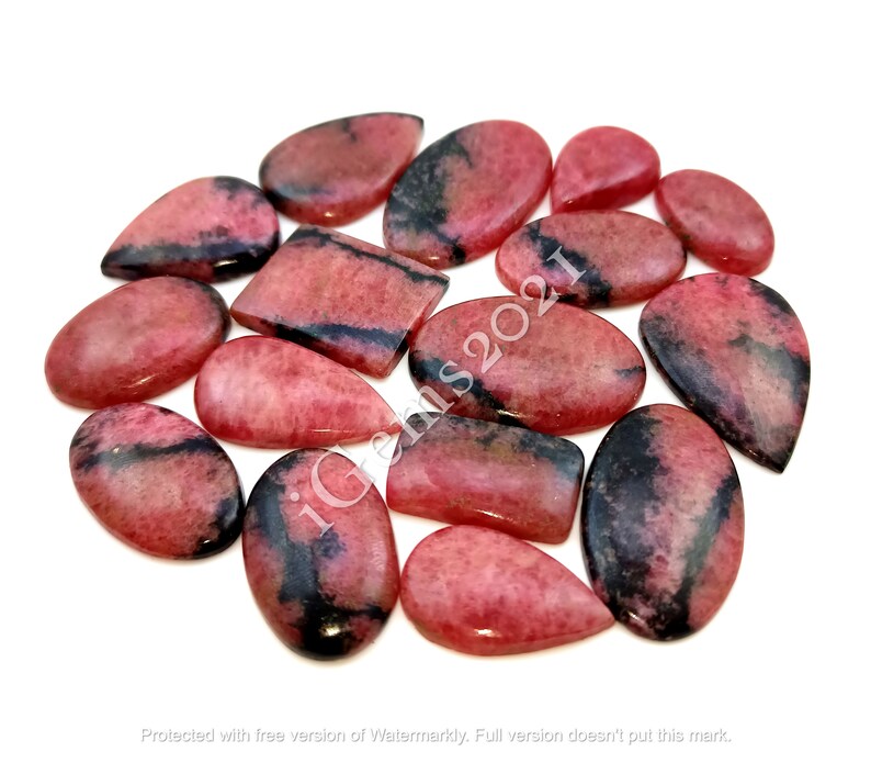 May include: A collection of 15 pink and black gemstone cabochons, cut in teardrop and rectangular shapes. The stones have a natural, polished finish.