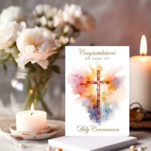 Może przedstawiać: Biała kartka z akwarelowym tłem w kolorze różowym, pomarańczowym, żółtym i niebieskim, z drewnianym krzyżem w środku. Na kartce napis "Gratulacje z okazji Pierwszej Komunii Świętej".
