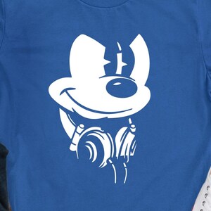May include: A blue t-shirt with a white graphic of a cartoon mouse head wearing headphones. The mouse has a smiling face and large ears. The headphones are depicted with curved lines.