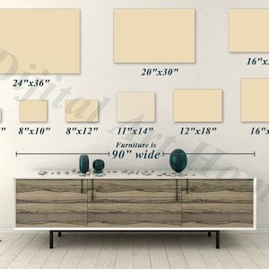 May include: A display of various sized beige rectangular canvases, ranging from 5"x7" to 24"x36", are arranged on a white wall. The text "Furniture is 90" wide" is displayed below the canvases. A modern white and wood-tone cabinet is below the text.
