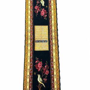 May include: A rectangular decorative panel featuring a black central field with two birds perched on flowering branches with pink blossoms. A central yellow rectangular cartouche contains columns of black script. The border is yellow with floral motifs.
