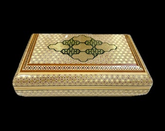 May include: A rectangular wooden box with a decorative inlaid design. The box is made of light wood with gold and brown accents. The top of the box features a geometric pattern with a central diamond shape.