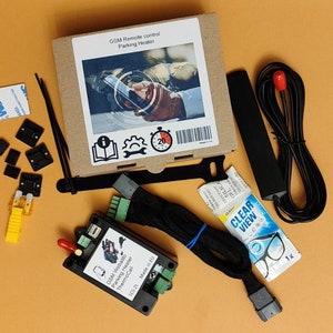 May include: A black and green electronic device with the text "GSM Webasto Parking Heater ThermoCall TCS 21 Made in EU" on it. The device is surrounded by various other items, including a black antenna, a black cable, a clear plastic bag with the text "CLEAR VIEW" on it, and a small box with the text "GSM Remote control Parking Heater" on it.