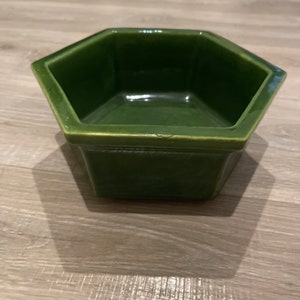 May include: A green hexagonal ceramic planter with a smooth, glossy finish.
