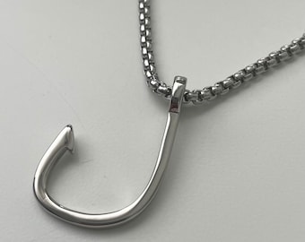 以下が含まれることがあります： シルバーのチェーンネックレスに、シルバーの釣り針のペンダントが付いている。