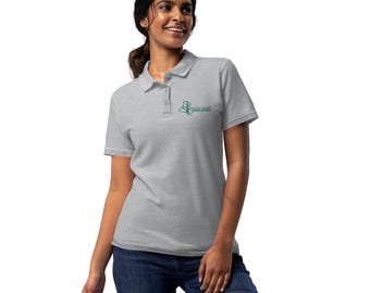 May include: A light gray polo shirt with short sleeves and a collared neckline. The shirt features a small green logo on the left chest. The model is wearing blue jeans.