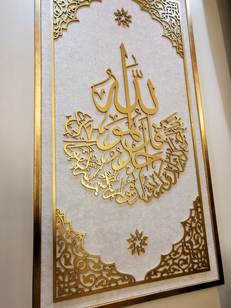 May include: A gold framed wall art piece with intricate Islamic calligraphy in a white background. The calligraphy is in Arabic and reads "Allah" in the center.