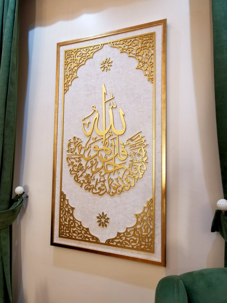 May include: A gold framed wall art piece with intricate cut-out designs. The center features a large Arabic calligraphy inscription in gold.