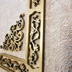 K&ouml;nnte beinhalten: Eine goldfarbene dekorative Wandverkleidung mit filigranen, geschnitzten Blumenmustern. Die Verkleidung ist aus Holz und hat ein erhabenes, dreidimensionales Design.