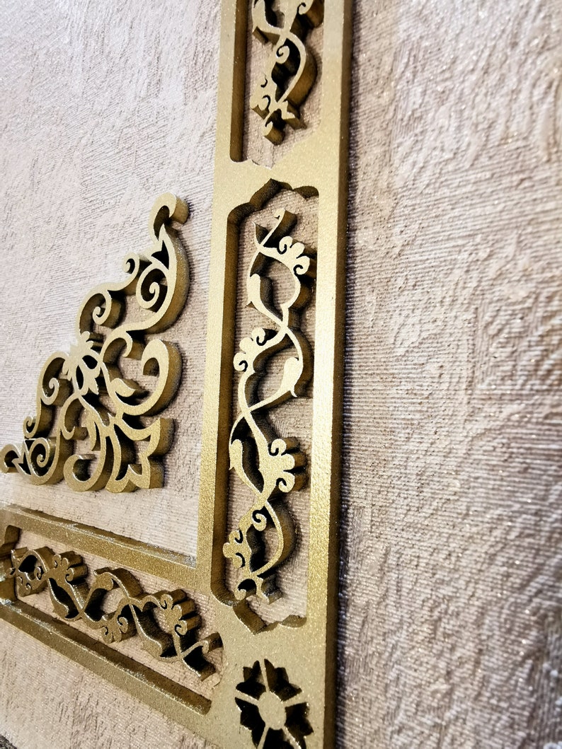 K&ouml;nnte beinhalten: Eine goldfarbene dekorative Wandverkleidung mit filigranen, geschnitzten Blumenmustern. Die Verkleidung ist aus Holz und hat ein erhabenes, dreidimensionales Design.