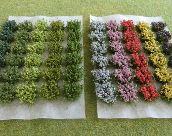 May include: A set of 40 miniature green and colorful bushes for model railroading or other hobby projects. The bushes are arranged in rows on a white surface.