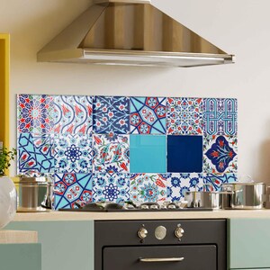 May include: A patterned kitchen splashback composed of various tiles in blue, red, and white. The design incorporates floral and geometric motifs, providing a colourful and artistic element above the hob. The tiles are arranged in a mosaic style.
