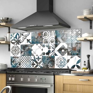 May include: Kitchen backsplash with patterned tiles in blue, white, and grey. The tiles are arranged in a grid above a stainless steel stove. The design adds a decorative element to the kitchen, complementing the wooden cabinets and extractor hood.