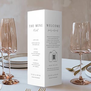 Peut inclure: Mise en place de mariage avec des flûtes à champagne, des couverts dorés et un menu blanc. Le menu affiche "THE MENU" et "WELCOME", un menu et un code QR pour partager des photos.