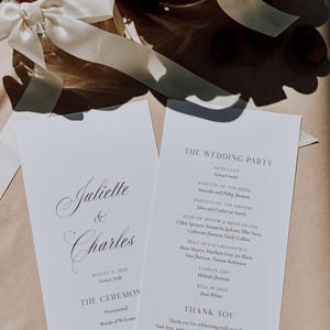 Puede incluir: Dos programas de boda blancos con caligrafía elegante. El primer programa dice "Juliette & Charles" con la fecha y el lugar. El segundo programa enumera la fiesta de bodas. Una cinta blanca con un anillo está en el fondo.
