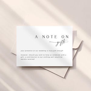 Op de afbeelding: Een witte kaart met zwarte tekst die "A Note On gifts" luidt en uitlegt dat de aanwezigheid van het paar op hun bruiloft een cadeau is, maar als gasten willen bijdragen aan hun wensput, dan wordt dat hartelijk gewaardeerd.