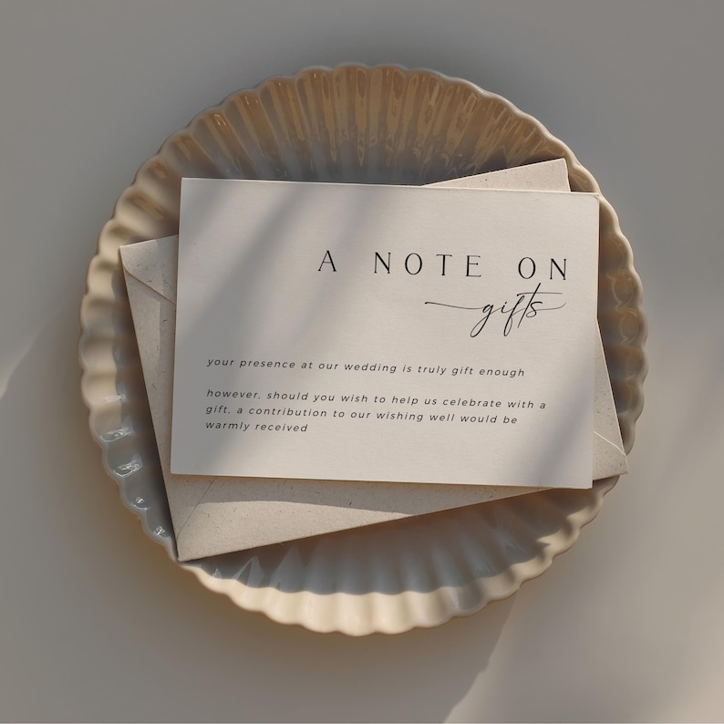 Op de afbeelding: Een kaartje met de tekst "A Note On Gifts" en de boodschap "Uw aanwezigheid op onze bruiloft is al een cadeau op zich, maar mocht u ons toch willen verrassen met een cadeau, dan is een bijdrage in onze wensbox van harte welkom."
