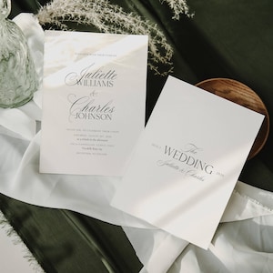 May include: Two white wedding invitation cards with elegant calligraphy. The first card reads "Juliette Williams & Charles Johnson" and includes event details. The second card says "The Wedding" and the names "Juliette & Charles".