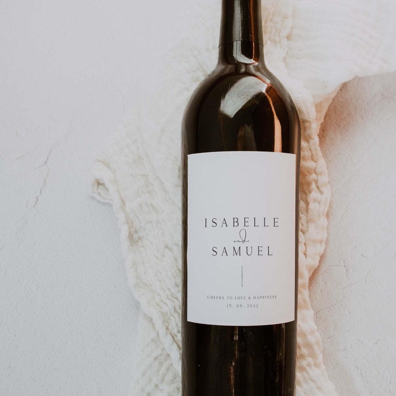 May include: A white wine bottle label with the text "Isabelle & Samuel" and the date "15.09.2022" with the words "Cheers to love & happiness".