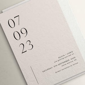 May include: A minimalist wedding save the date card with the date "07 09 23" printed in black on a white background. The text "OLIVIA + CHRIS are getting married on SATURDAY, 5TH SEPTEMBER, 20XX santa monica, CA formal invitation to follow" is printed in black at the bottom of the card.