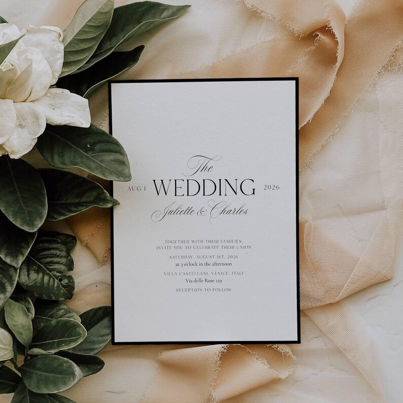 May include: A wedding invitation with a black border, featuring the text "The Wedding" and the names "Juliette & Charles." The date is August 1, 2026. The invitation is on a white background with floral and fabric accents.