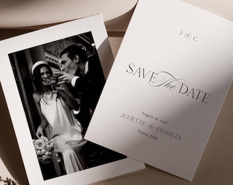 May include: Black and white photograph of a couple toasting champagne glasses, next to a white card with the text "SAVE The DATE" and the names Juliette & Charles, August 16, 2026, Venice, Italy.