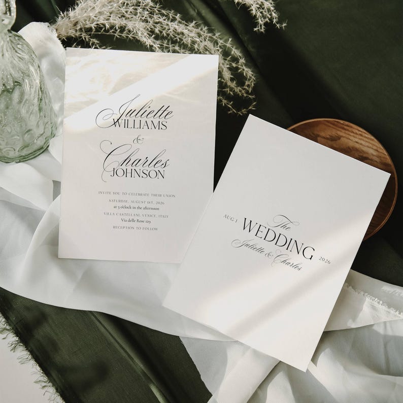 May include: Two white wedding invitation cards with elegant black script. One card displays the names "Juliette Williams & Charles Johnson" and event details. The other card reads "The Wedding" and the names "Juliette & Charles" with the year 2026.
