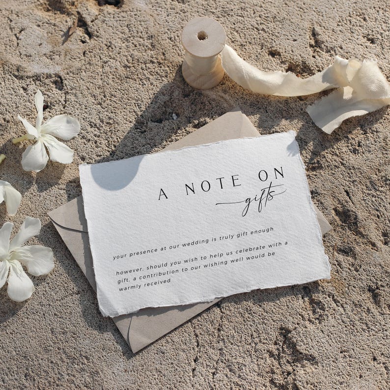Op de afbeelding: Een kaartje met de tekst "A Note On Gifts" geschreven in zwarte cursieve letters. De tekst eronder luidt: "Uw aanwezigheid op onze bruiloft is al een geweldig cadeau, maar mocht u ons willen helpen met het vieren van onze dag met een cadeau, dan is een bijdrage aan onze wensfontein van harte welkom."