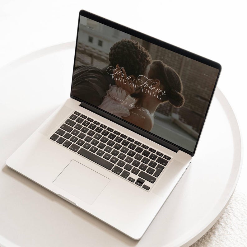 K&ouml;nnte beinhalten: Ein silberner Laptop, der eine Website mit dem Text "It's a Forever Kind of Thing" &uuml;ber einem Bild eines sich k&uuml;ssenden Paares anzeigt. Der Laptop steht auf einem wei&szlig;en, runden Tisch. Die Website enth&auml;lt auch die Namen "Veronica & Cristino" und "Since 1998."