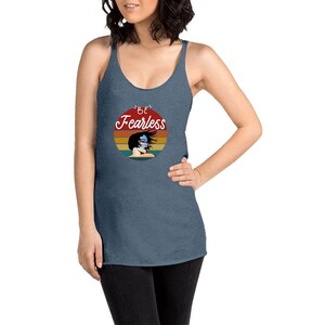 May include: A blue tank top with a vintage-style graphic of a woman with windblown hair. The graphic says "Be Fearless" in a white script font.