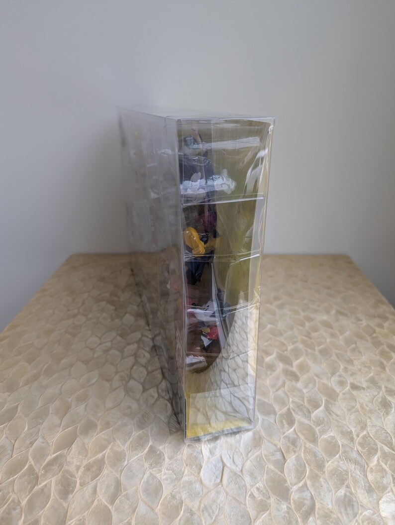 Puede incluir: Una vitrina de pl&aacute;stico transparente y rectangular que contiene varias figuras peque&ntilde;as y coloridas. La vitrina est&aacute; sellada y se encuentra sobre una superficie clara y estampada. Las figuras son visibles a trav&eacute;s del pl&aacute;stico transparente.