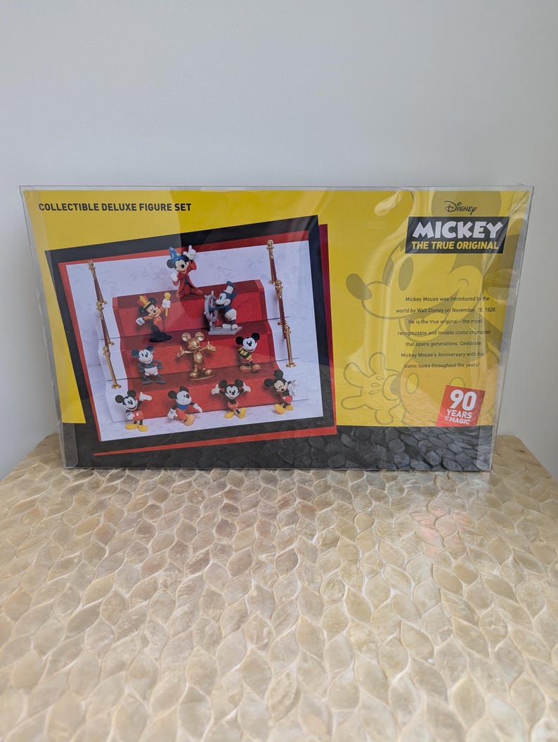Puede incluir: Set de figuras de lujo coleccionables con Mickey Mouse. El set incluye m&uacute;ltiples figuras de Mickey Mouse en varias poses. El embalaje es amarillo y negro, con el texto "Mickey The True Original" y "90 Years of Magic".