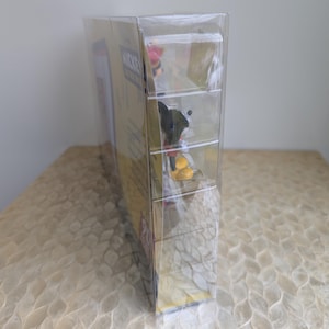Puede incluir: Una figura de Mickey Mouse en caja, encerrada en pl&aacute;stico transparente. La caja es amarilla con texto rojo y negro. La figura es visible a trav&eacute;s del pl&aacute;stico, mostrando a Mickey Mouse con su atuendo cl&aacute;sico. El embalaje est&aacute; sellado.