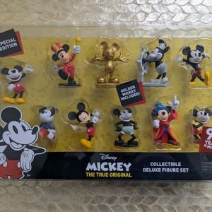 Puede incluir: Un juego de figuras de lujo coleccionables con diez figuras de Mickey Mouse en varias poses y atuendos. El juego incluye una figura dorada de Mickey y celebra 90 a&ntilde;os de magia. Las figuras se exhiben en un paquete de pl&aacute;stico transparente.