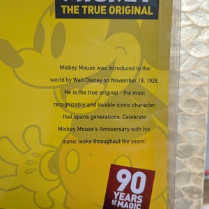 Puede incluir: Un fondo amarillo con el logotipo de Disney Mickey Mouse y el texto "THE TRUE ORIGINAL". El texto indica que Mickey Mouse fue presentado en 1928. Un emblema rojo y blanco dice "90 YEARS OF MAGIC".