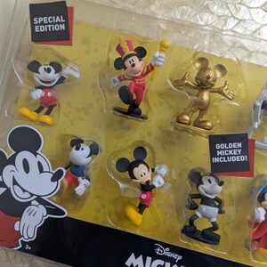 Puede incluir: Un juego de figuras de lujo con Mickey Mouse en varias poses. El juego incluye una figura dorada de Mickey y est&aacute; etiquetado como una edici&oacute;n especial. El embalaje muestra el logotipo de Disney Mickey The True Original.