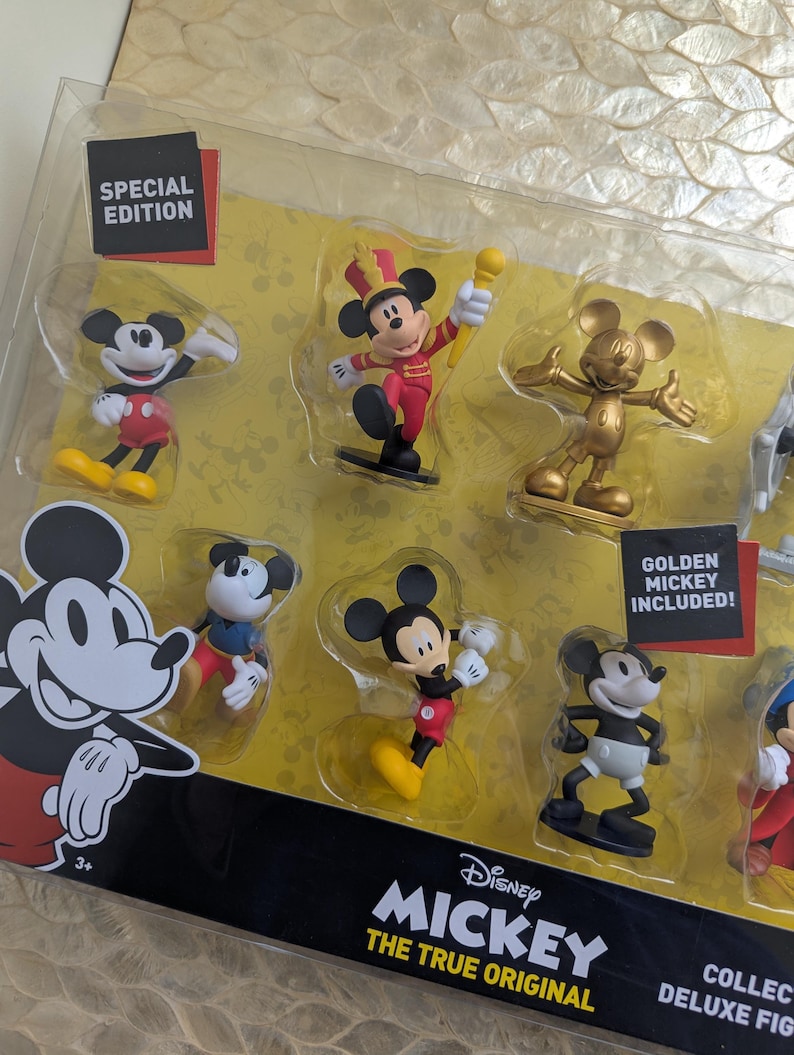 Puede incluir: Un juego de figuras de lujo con Mickey Mouse en varias poses. El juego incluye una figura dorada de Mickey y est&aacute; etiquetado como una edici&oacute;n especial. El embalaje muestra el logotipo de Disney Mickey The True Original.