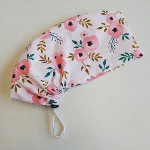 May include: A pink drawstring bag with a floral pattern featuring pink flowers and green leaves. The bag has a white drawstring.